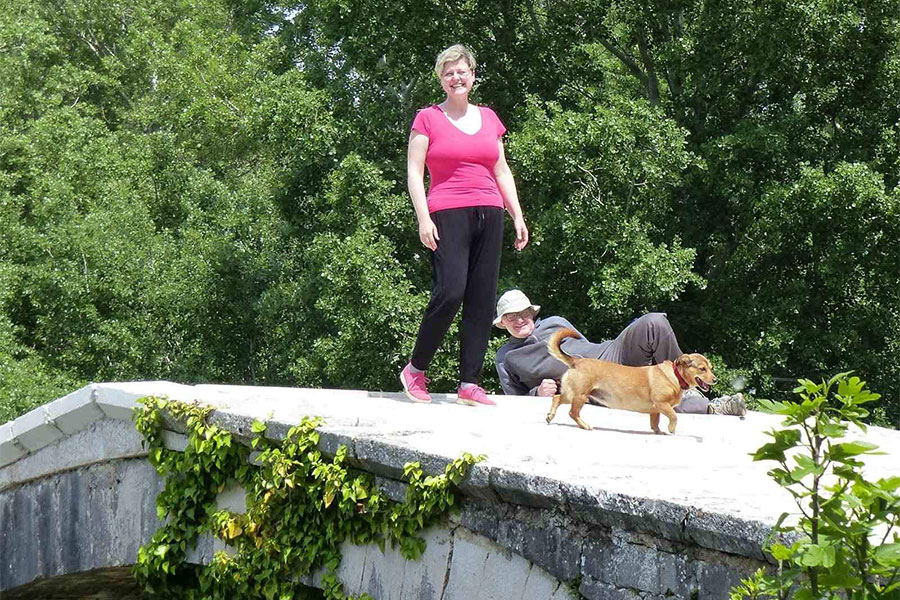 žena, muškarac i mali žuti pas na mostiću
