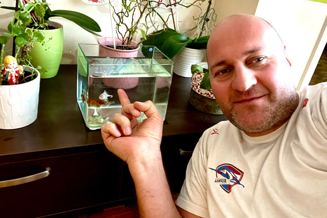 Čovjek pokazuje prstom na akvarijum u kojem su dvije ribice